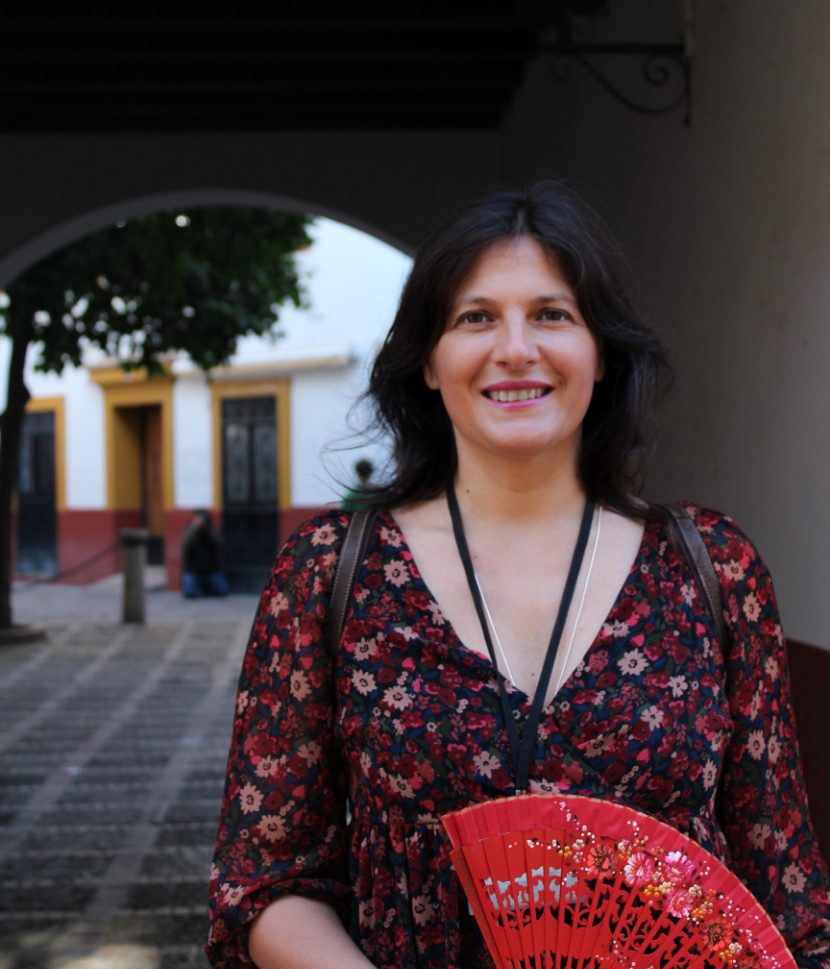 Alexia smiling in the narrow streets of Santa Cruz Area in Seville during a tour with her handmade fun.