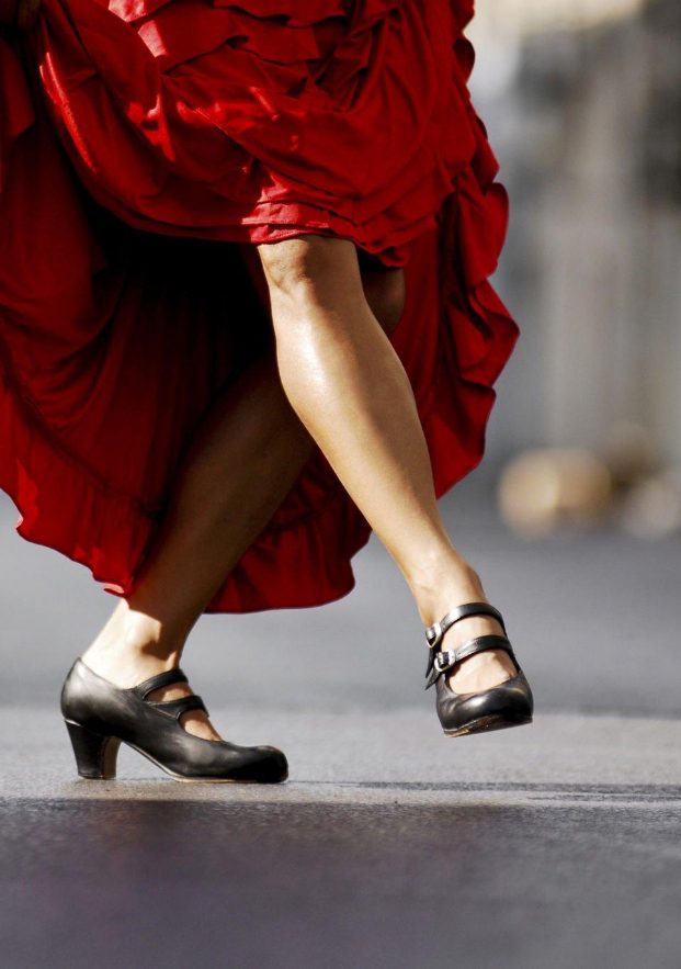 Detail of the feet of an Andalusian woman with her flamenco shoes and flamenco dress while dancing.