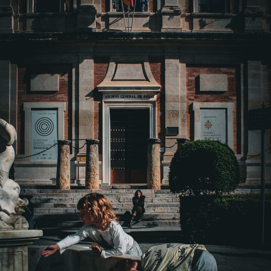 Children playing in a fountain and the Archivo General de Indias in the background during a relaxing moment on our private tour in Seville.