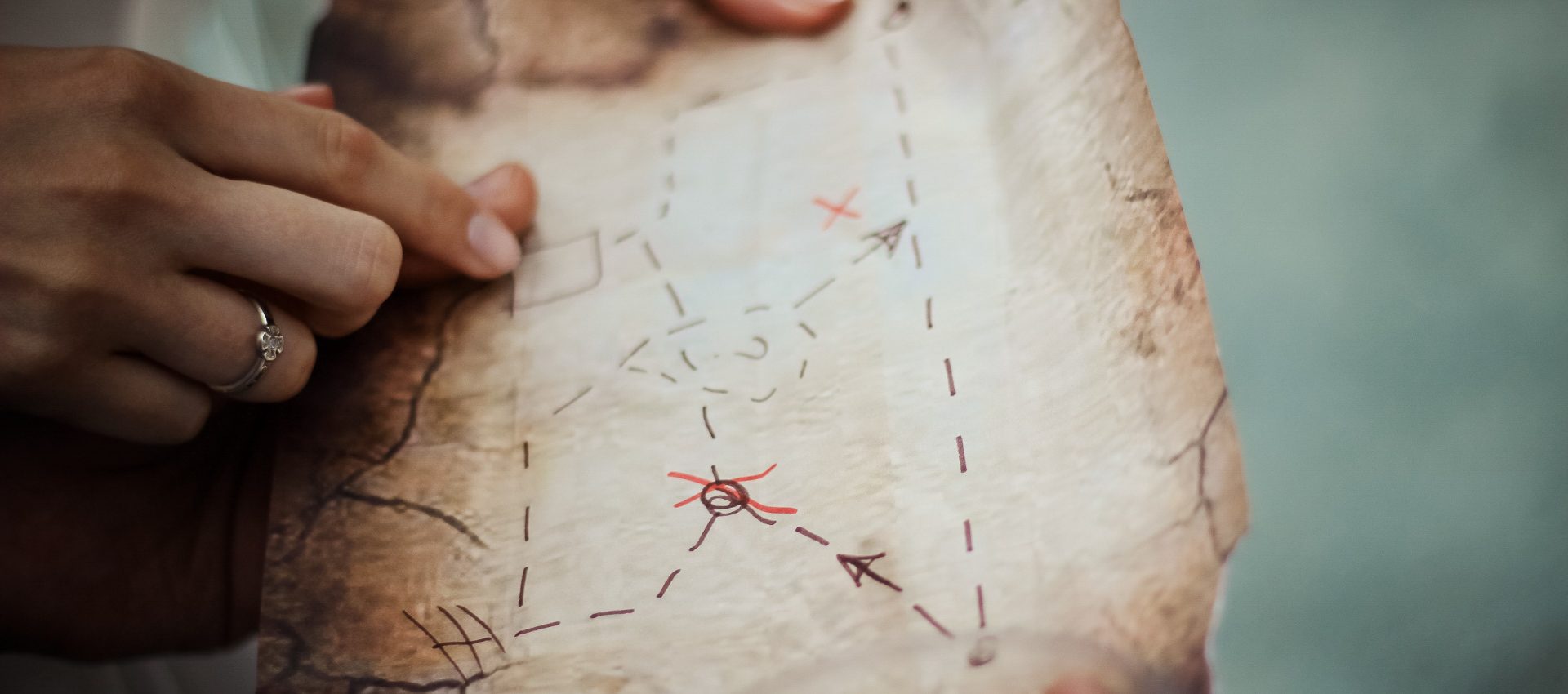 Piece of an old map being hold by a few hands and pointing possible locations of the Scavenger Hunt Tour.