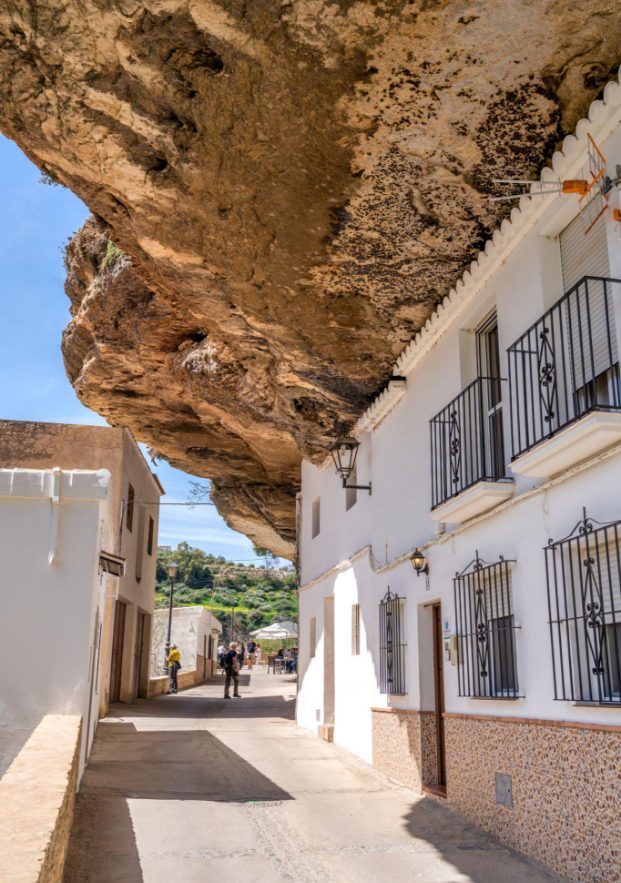 Street carved into the rock with the houses under its stone wall and its cobblestone pavement.