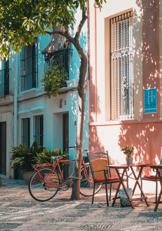 Corner of an Andalusian town with an orange tree, a terrace and a bicycle.